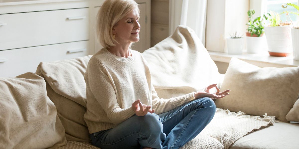 Frau meditiert auf dem Sofa